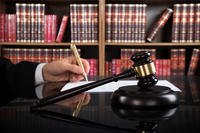 Judge Writing On Paper And Gavel At Desk